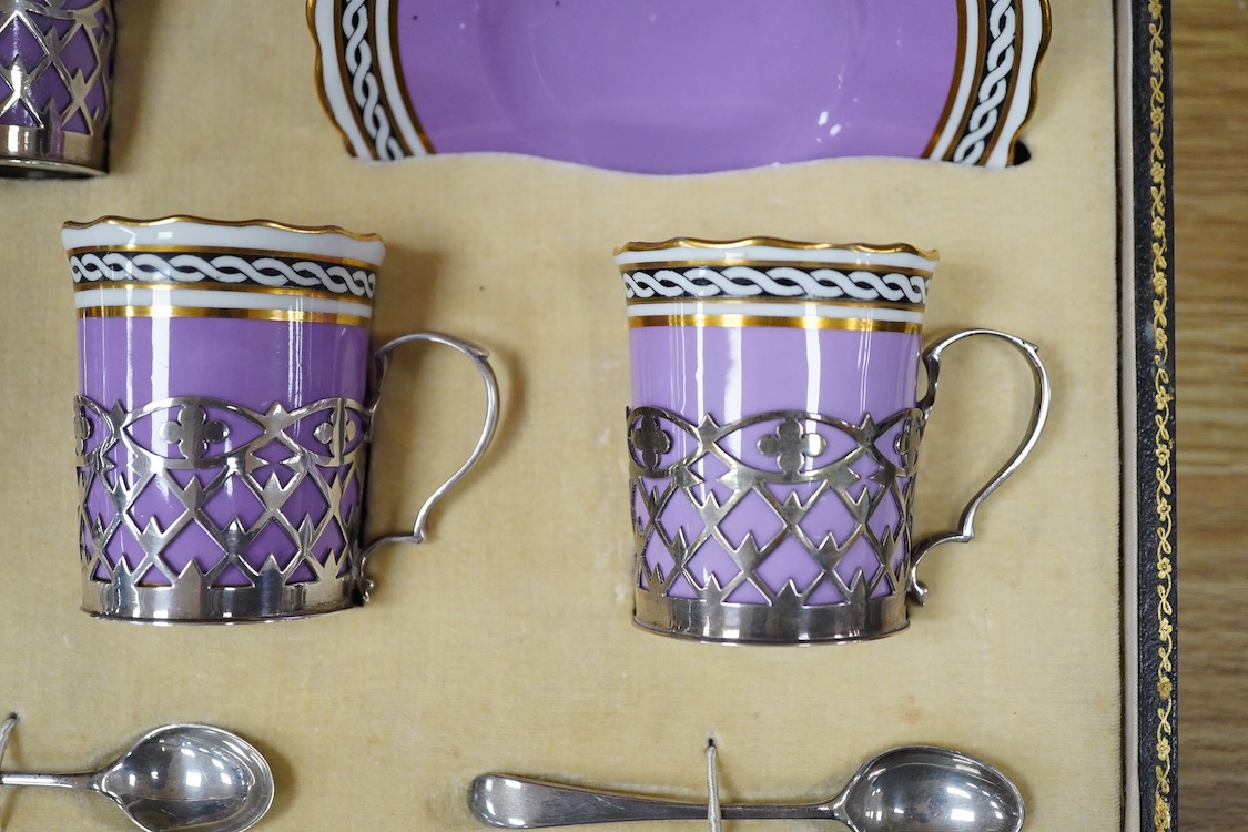A cased Aynsley coffee set with silver mounted coffee cans and silver teaspoons, William Hutton & Sons, Sheffield, 1924, the leather case 38cm wide